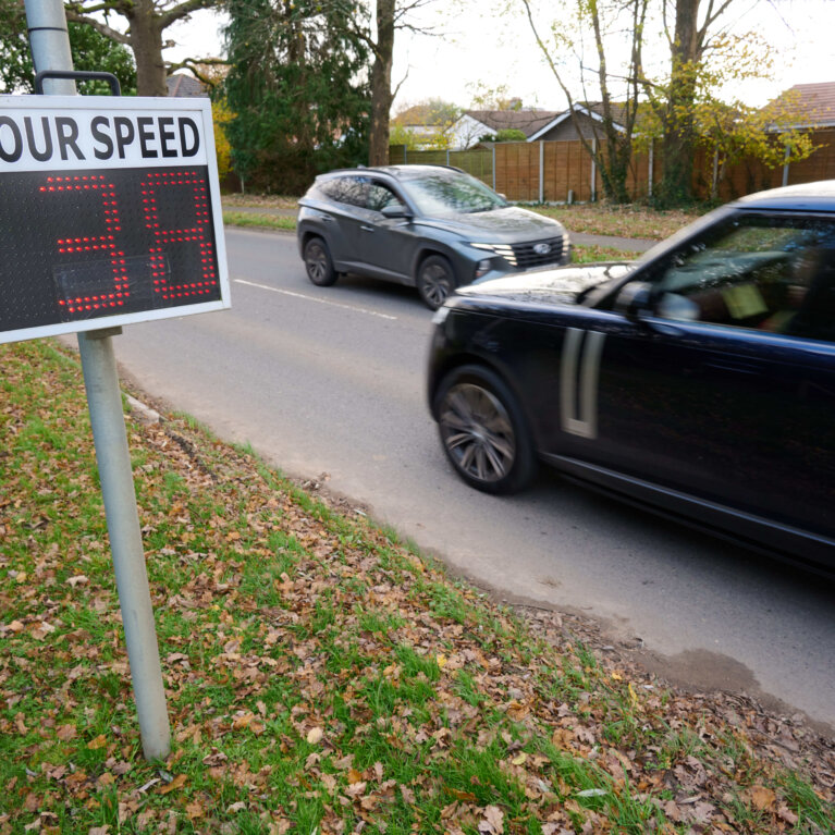 cars on road passing a sign showing speed travelling