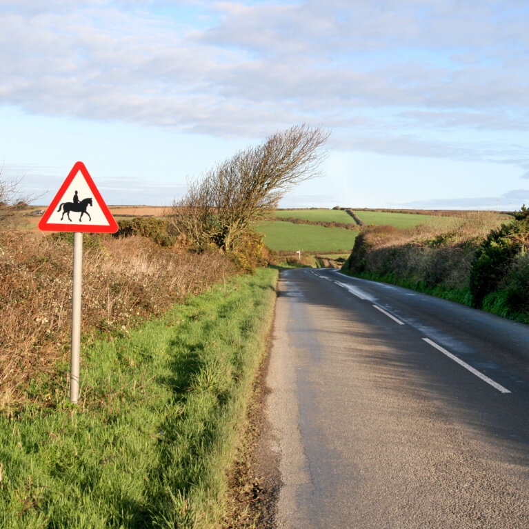 Country road with horse riders signpost